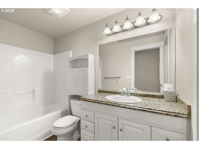 a bathroom with a granite countertop sink mirror vanity and toilet