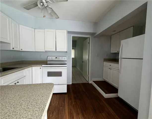 a kitchen with granite countertop a refrigerator and a stove top oven