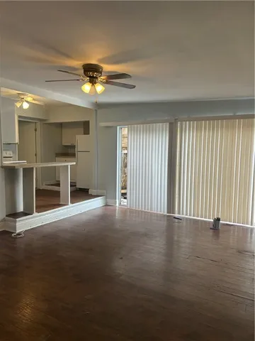 an empty room with windows and chandelier fan