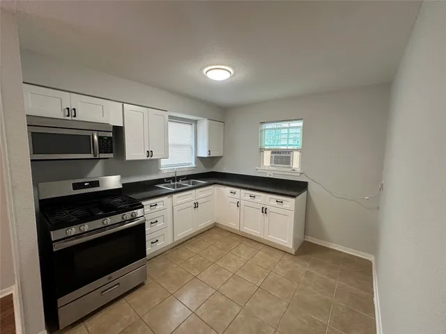 a kitchen with stainless steel appliances granite countertop a stove a sink and a microwave