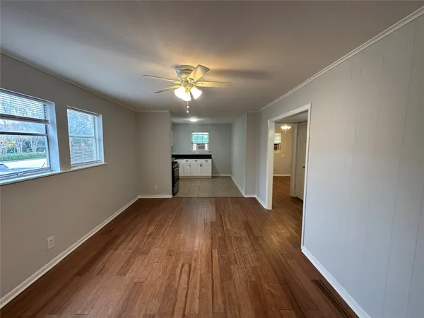 a view of empty room with wooden floor and fan