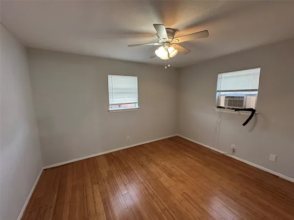 a view of a room with wooden floor and a ceiling fan