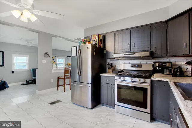 a kitchen with stainless steel appliances kitchen island granite countertop a refrigerator a stove a sink a dining table and chairs with wooden floor