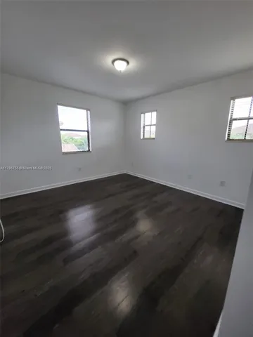 an empty room with wooden floor and windows in it