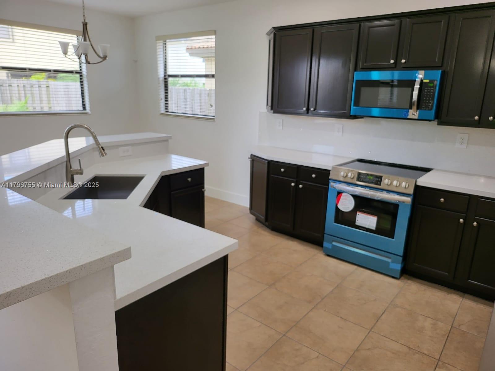 11729 Southwest 236th Street Homestead, FL 33032 - Photo 6 of 22 a kitchen with stainless steel appliances a stove a microwave sink and cabinets