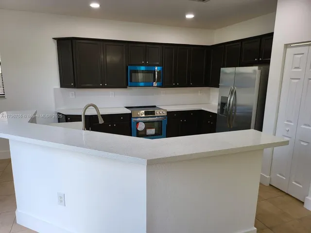 a kitchen with stainless steel appliances a refrigerator a sink a stove a microwave and cabinets