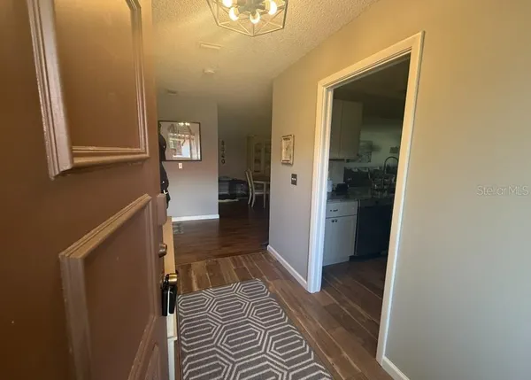 a view of a hallway with wooden floor and a bathroom