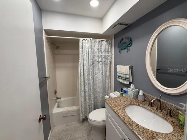 a bathroom with a granite countertop toilet a sink and a mirror