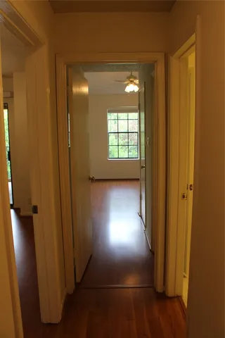 an empty room with a chandelier fan and wooden floor