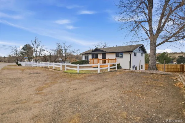 a view of a white house with a big yard and large trees