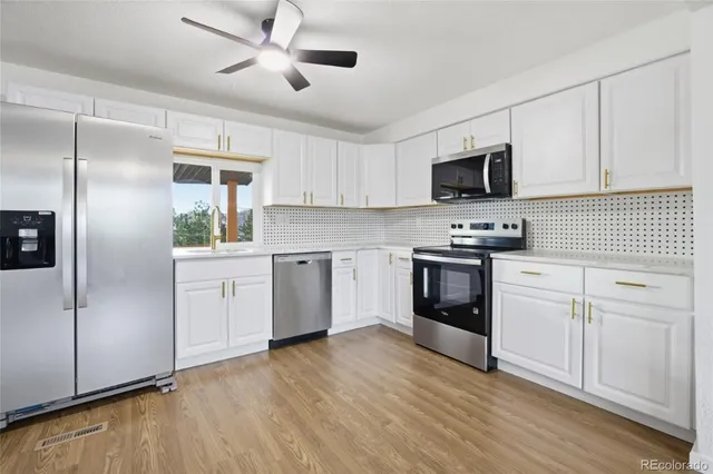 a kitchen with white cabinets stainless steel appliances and a refrigerator