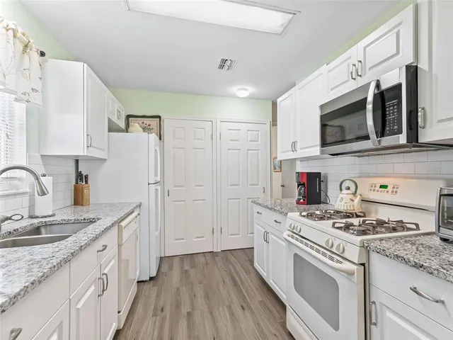 a kitchen with granite countertop white cabinets stainless steel appliances and sink