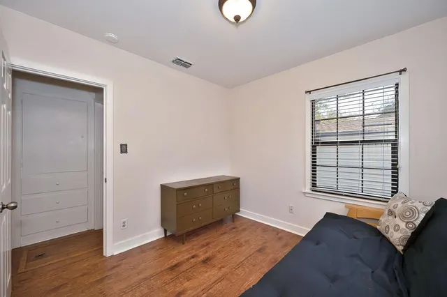 an empty room with wooden floor cabinet and windows