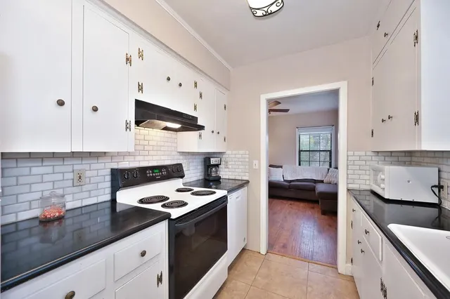 a kitchen with granite countertop cabinets a sink a stove and wooden floor