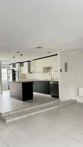 a living room with stainless steel appliances kitchen island granite countertop a sink and cabinets