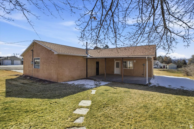 217 East 400 South Spring City, UT 84662 - Photo 46 of 71 Rear view of property featuring a lawn, a patio, stucco siding, and roof with shingles