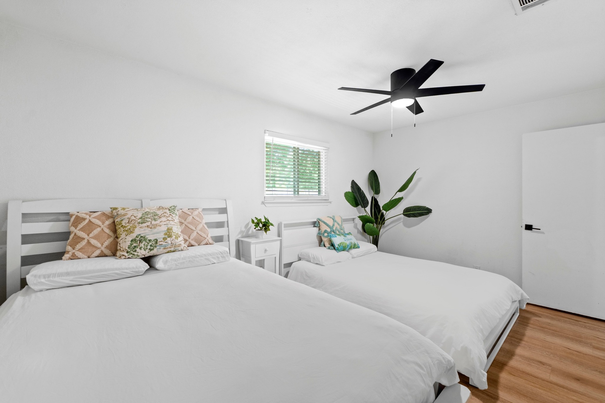 10601 Macmora Road, Unit B Austin, TX 78758 - Photo 16 of 22 A well-lit bedroom with rich wood flooring features a functional ceiling fan for optimal comfort.