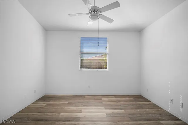 an empty room with a window and wooden floor