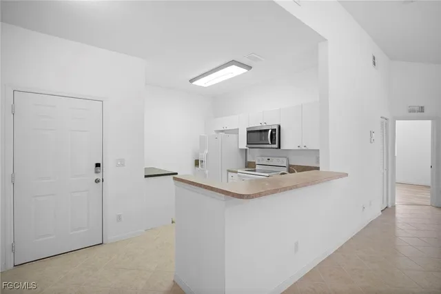 a living room with stainless steel appliances white cabinets and a refrigerator