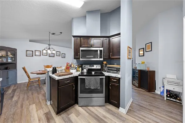 a kitchen with stainless steel appliances a stove a sink dishwasher a refrigerator and a dining table with wooden floor
