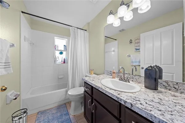 a bathroom with a granite countertop sink a toilet and bathtub