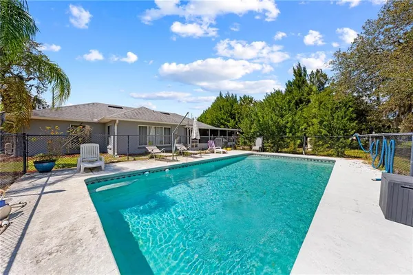 a view of a swimming pool with lawn chairs under an umbrella