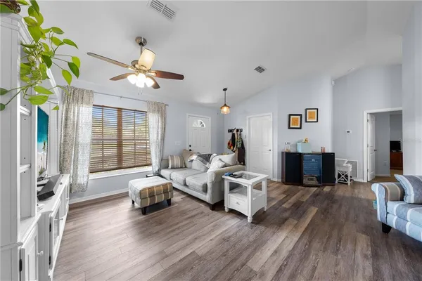 a living room with furniture two window and wooden floor