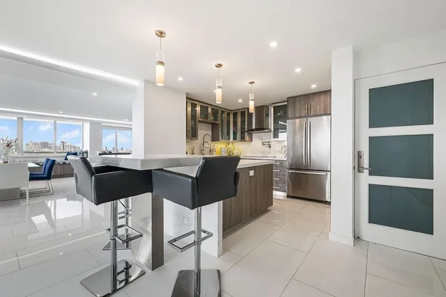 a kitchen with stainless steel appliances kitchen island granite countertop a refrigerator and a sink