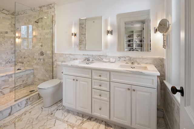 a bathroom with a granite countertop toilet sink shower and mirror