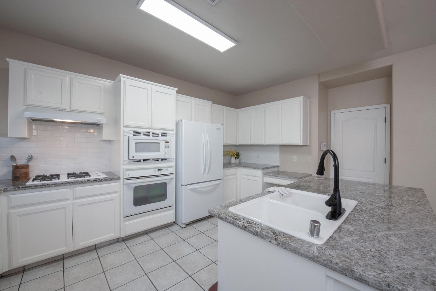 1847 Goshen Avenue Clovis, CA 93611 - Photo 8 of 39 a kitchen with white cabinets a sink stove and refrigerator