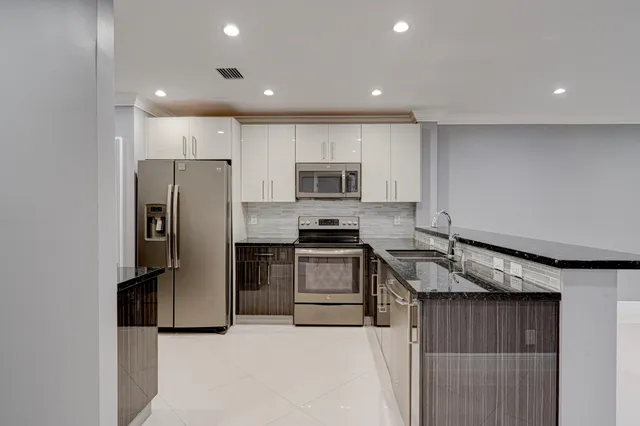 a kitchen with granite countertop a refrigerator and a stove top oven