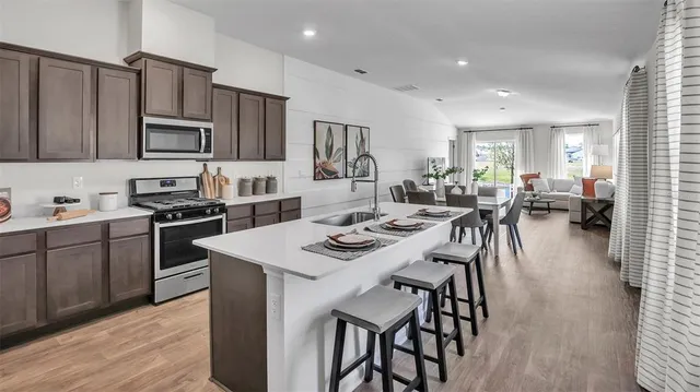 a kitchen with stainless steel appliances kitchen island granite countertop a stove a sink a dining table and chairs