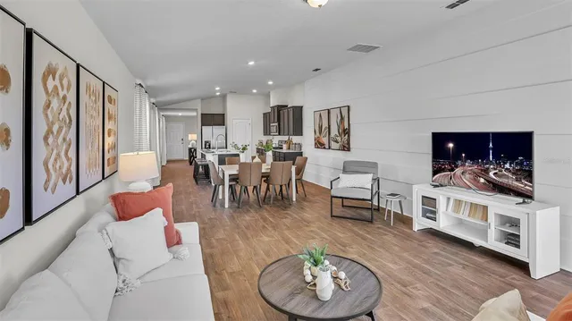 a living room with furniture kitchen view and a large window