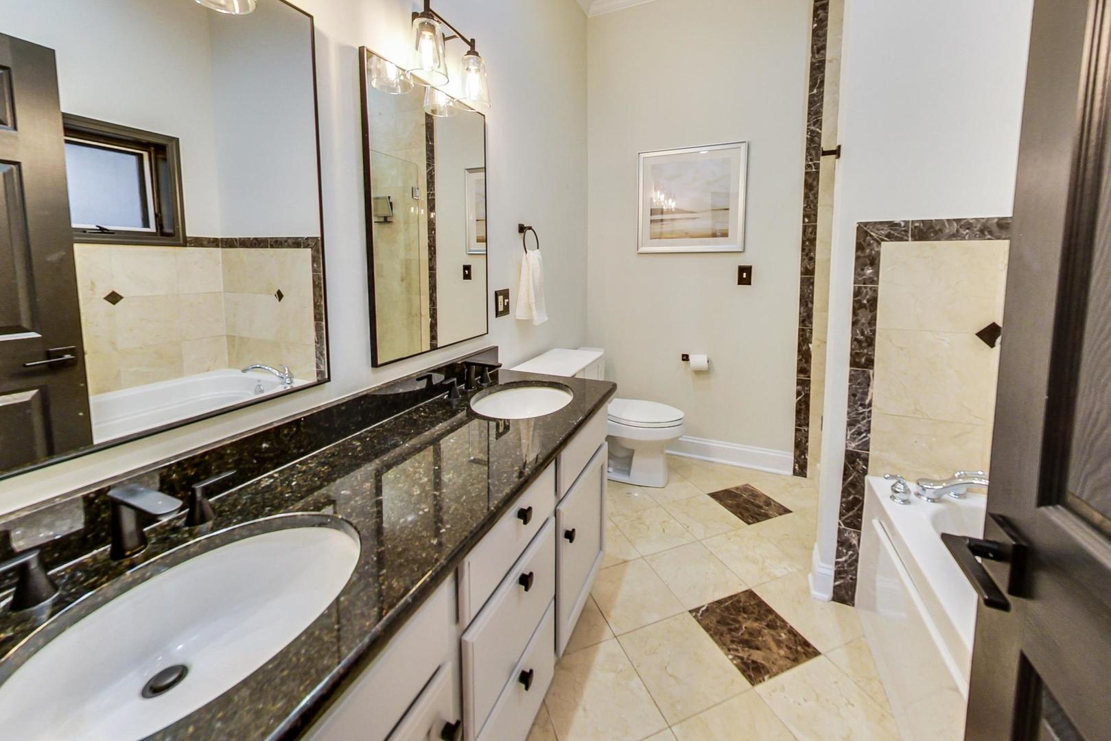 933 West Wolfram Street, Unit 2 Chicago, IL 60657 - Photo 14 of 24 a bathroom with a granite countertop double vanity sink and mirror