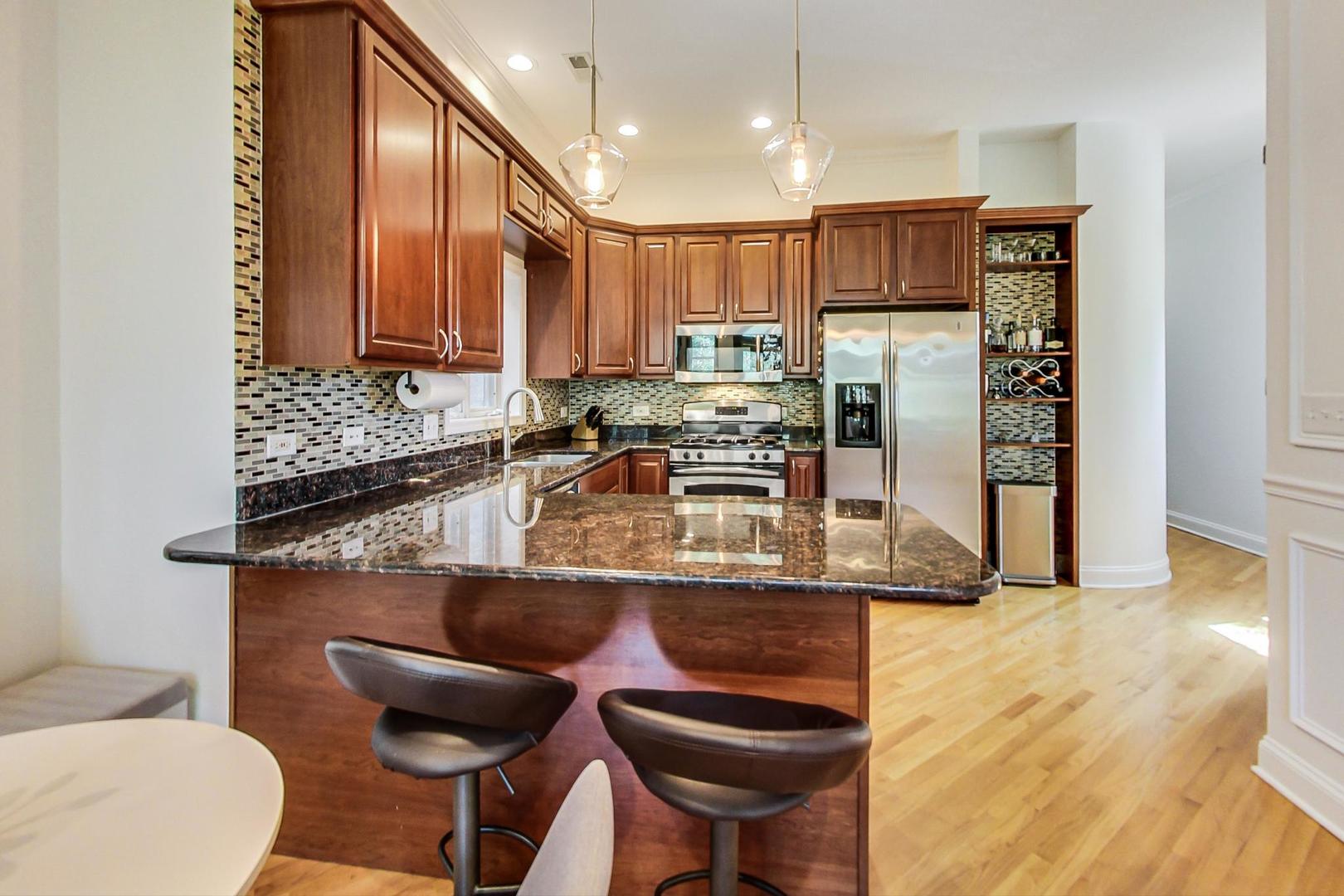 933 West Wolfram Street, Unit 2 Chicago, IL 60657 - Photo 8 of 24 a kitchen with stainless steel appliances granite countertop a sink and a refrigerator