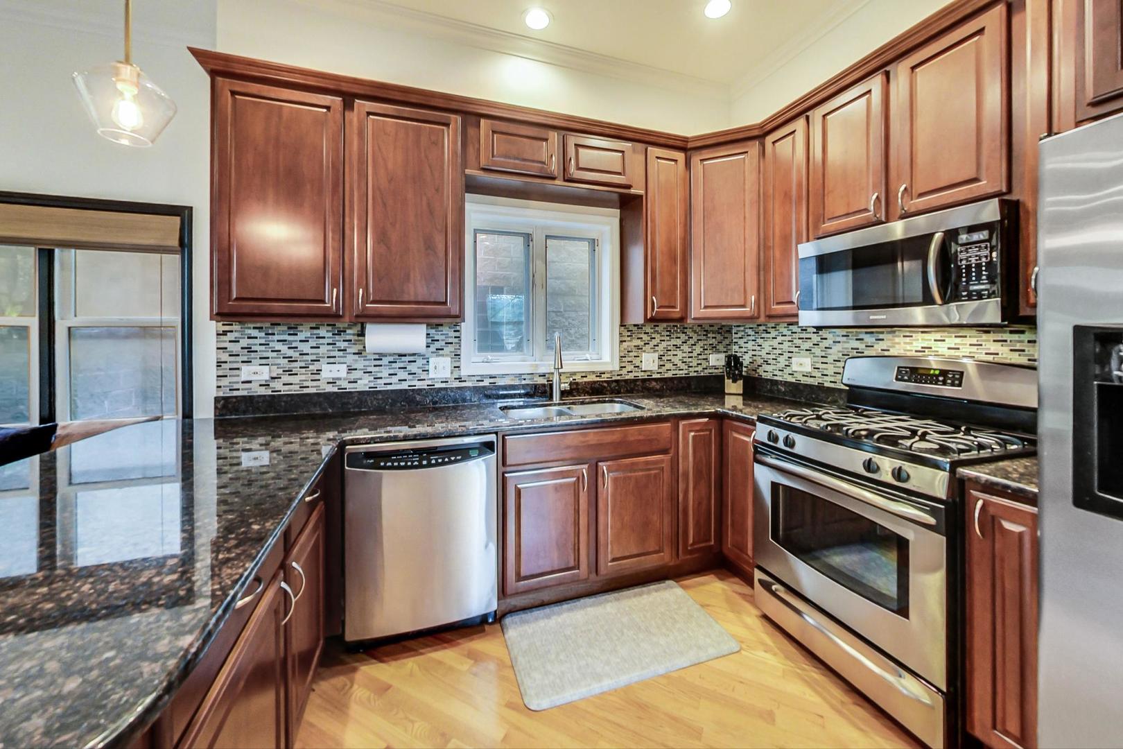 933 West Wolfram Street, Unit 2 Chicago, IL 60657 - Photo 9 of 24 a kitchen with stainless steel appliances granite countertop a stove microwave and sink