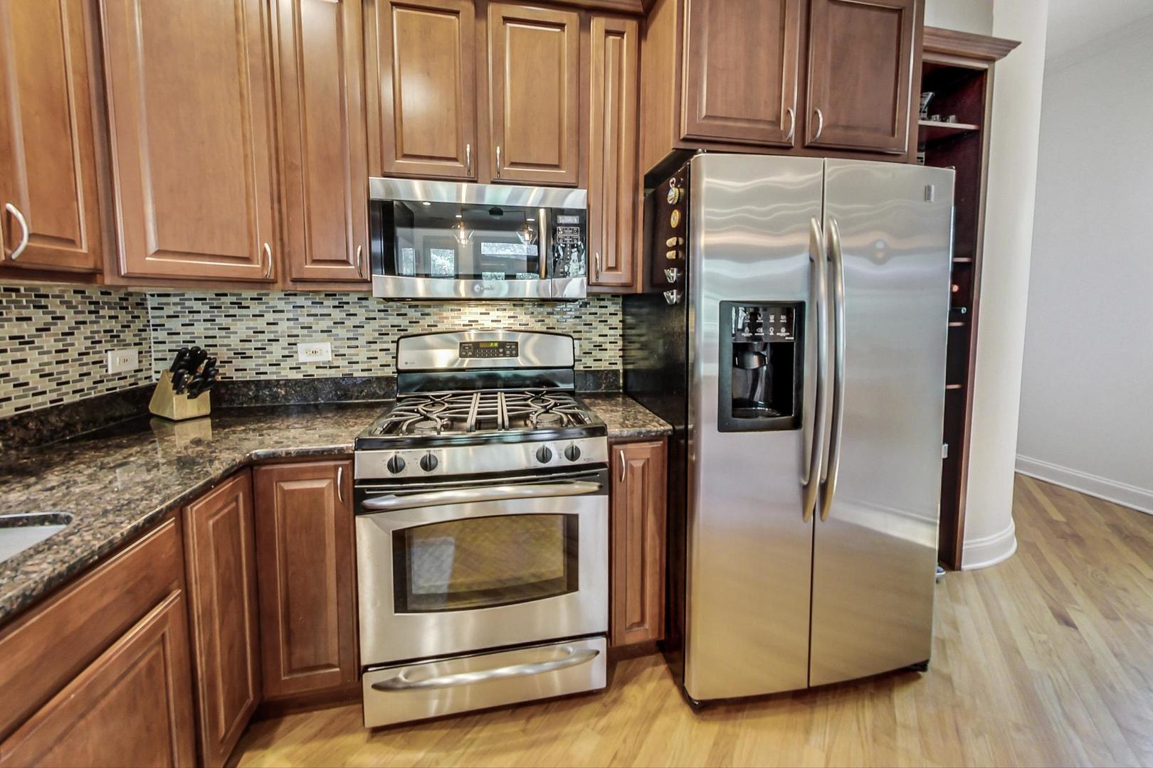 933 West Wolfram Street, Unit 2 Chicago, IL 60657 - Photo 10 of 24 a kitchen with granite countertop wooden cabinets and a stove top oven