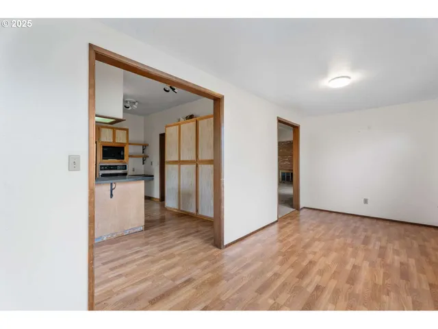 a view of an empty room with chandelier fan and window