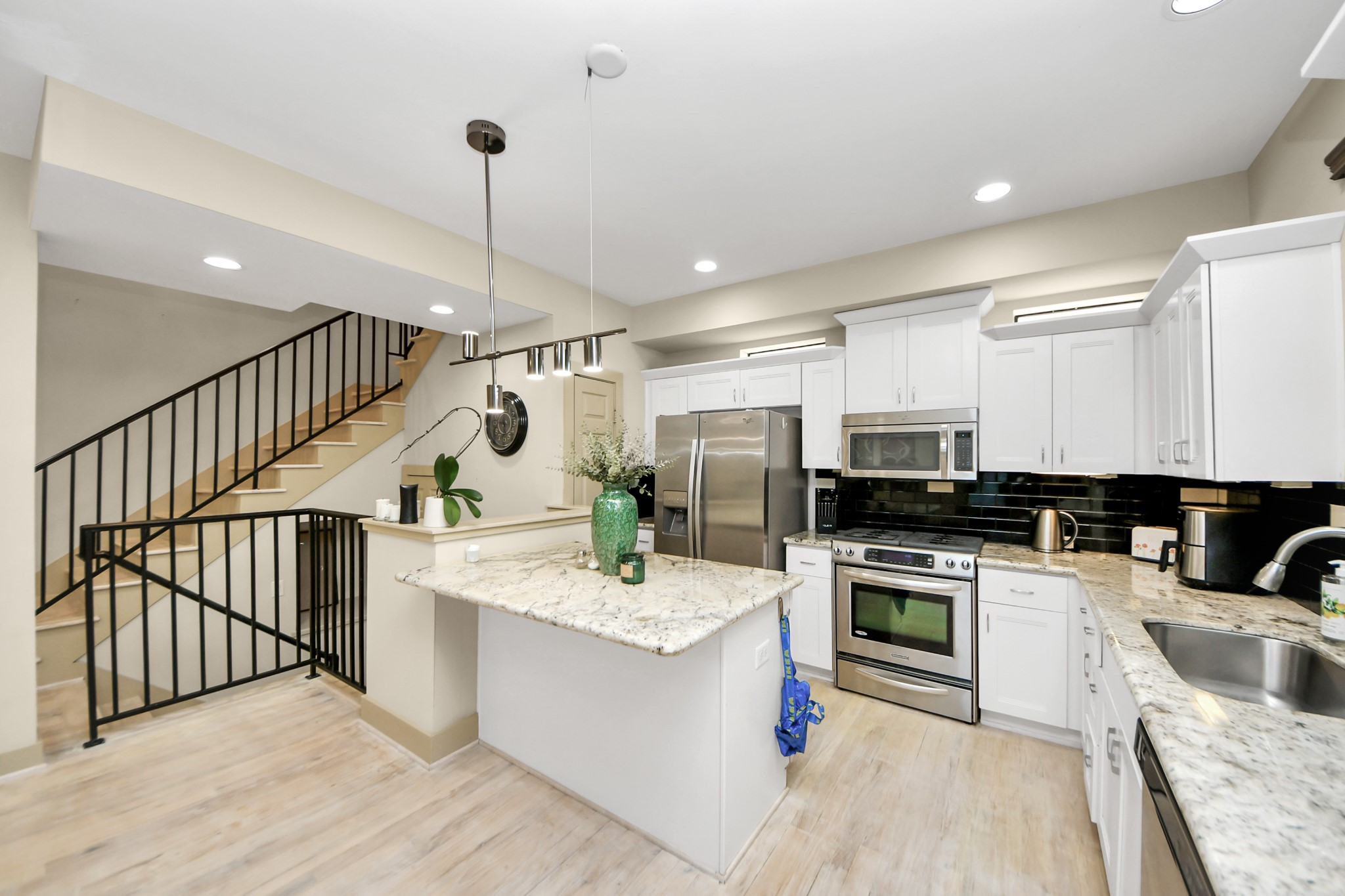 4510 Inker Street, Unit B Houston, TX 77007 - Photo 11 of 43 a large white kitchen with stainless steel appliances kitchen island a stove a sink dishwasher and a refrigerator with wooden floor