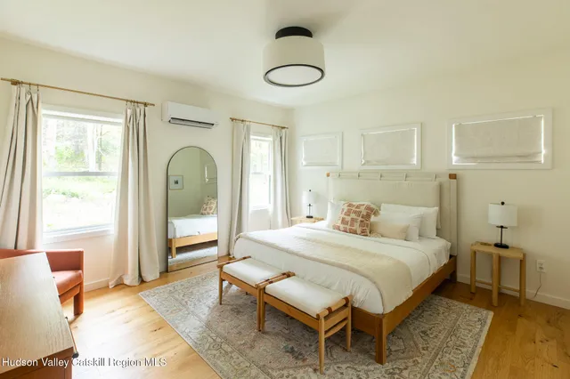 a bedroom with a bed a table and large windows