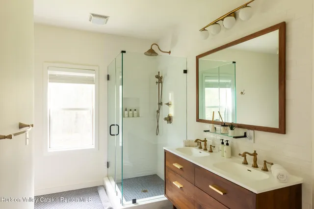 a bathroom with a double vanity sink mirror and shower