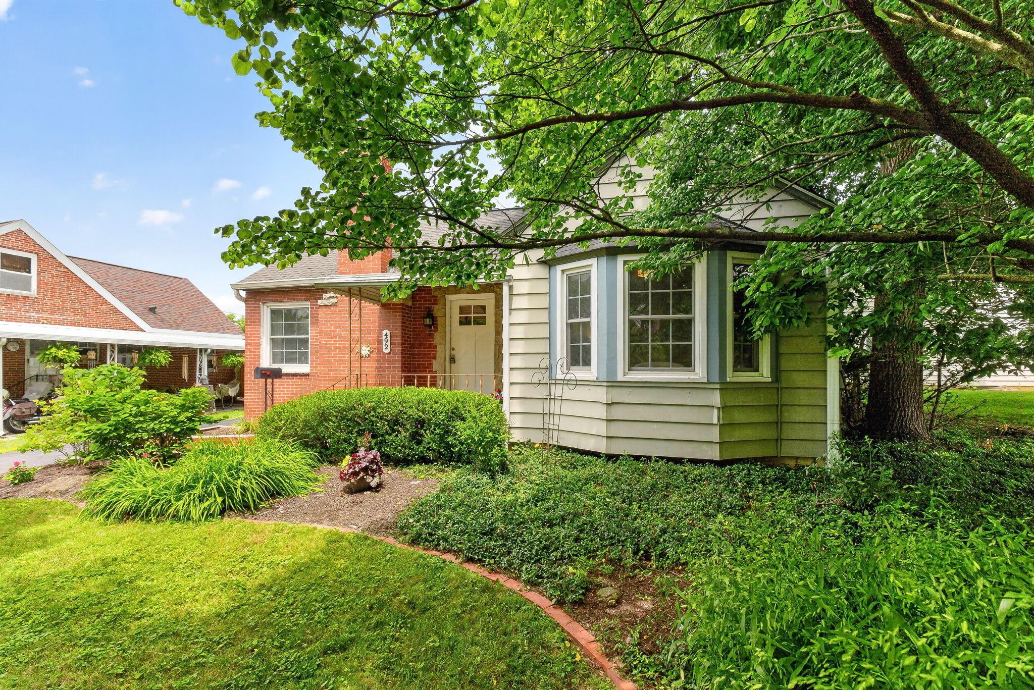492 Wetmore Road Columbus, OH 43214 - Photo 7 of 55 Brick and siding exterior featuring a bay window, white paneled entry door, and a covered porch
