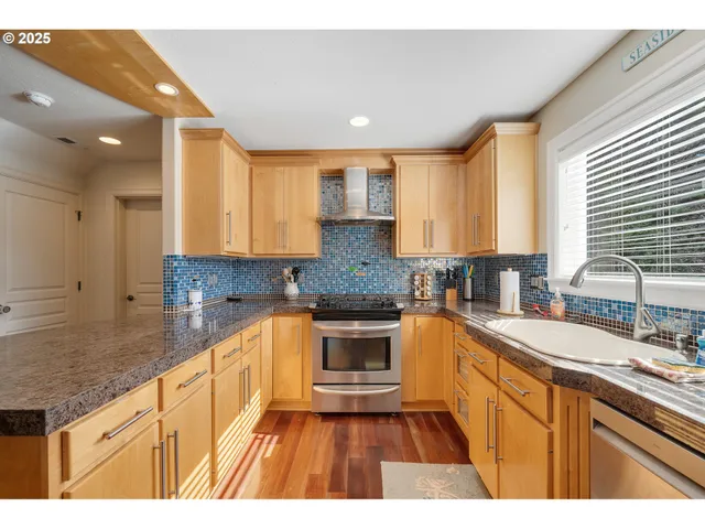 a kitchen with stainless steel appliances granite countertop a stove a sink and a refrigerator with wooden floor