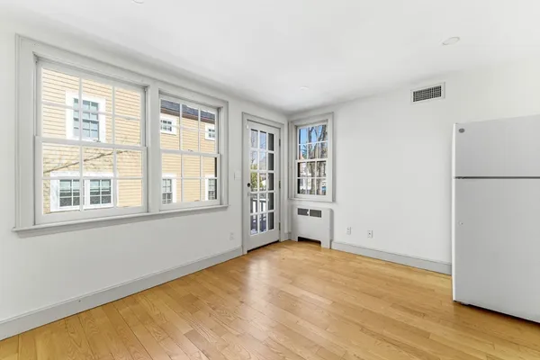 a view of an empty room with a window and wooden floor
