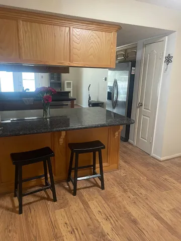 a kitchen with stainless steel appliances granite countertop a table chairs in it and wooden floors