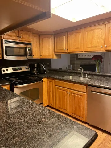 a kitchen with stainless steel appliances granite countertop a stove a sink and a microwave