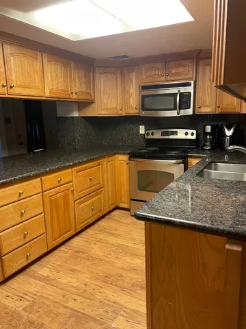 a kitchen with stainless steel appliances granite countertop a stove a sink and a microwave