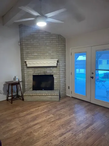 a view of an empty room with wooden floor and a fireplace