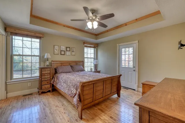 a bedroom with a bed and a large window with wooden floor