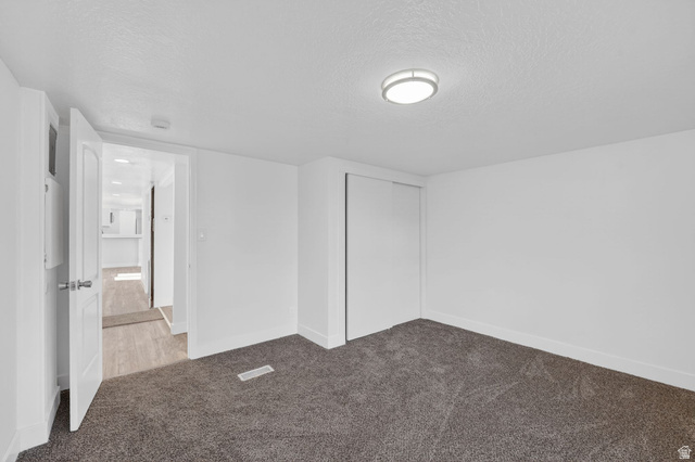 2491 Highway 89, Unit 523 Pleasant View, UT 84404 - Photo 16 of 31 Unfurnished bedroom featuring light carpet, a closet, and a textured ceiling